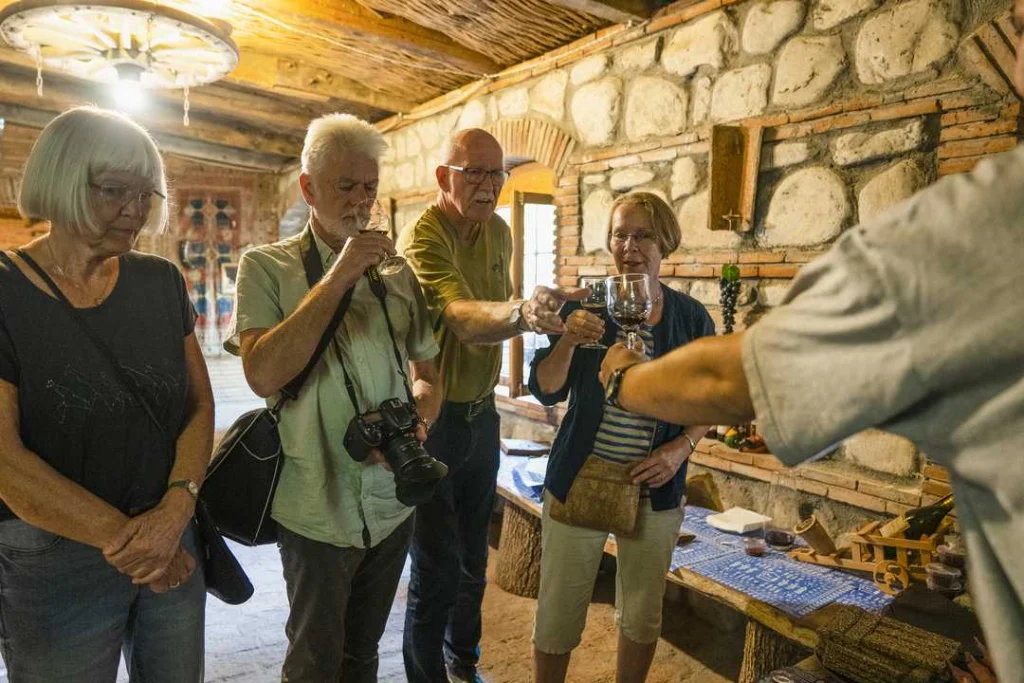 Wine House Gurjaani — Guests gather inside a stone-walled tasting room with traditional wooden ceiling beams.