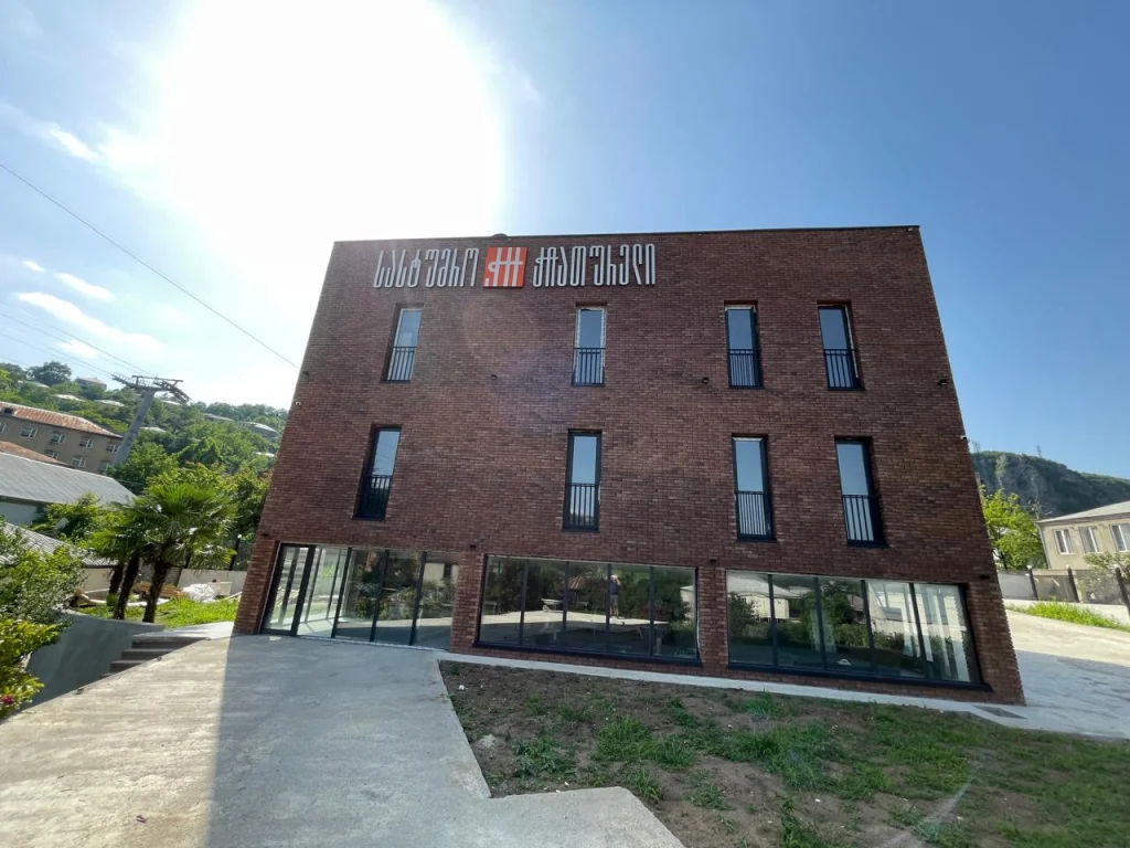 Winery Solomone — Brick multi-story building exterior with balconies, large windows, and hillside backdrop.