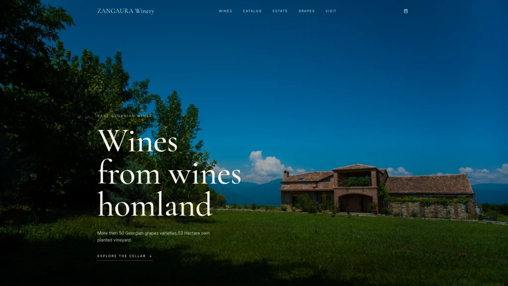 Zangaura — Wide view of the stone estate building set among green vineyards with mountains behind.