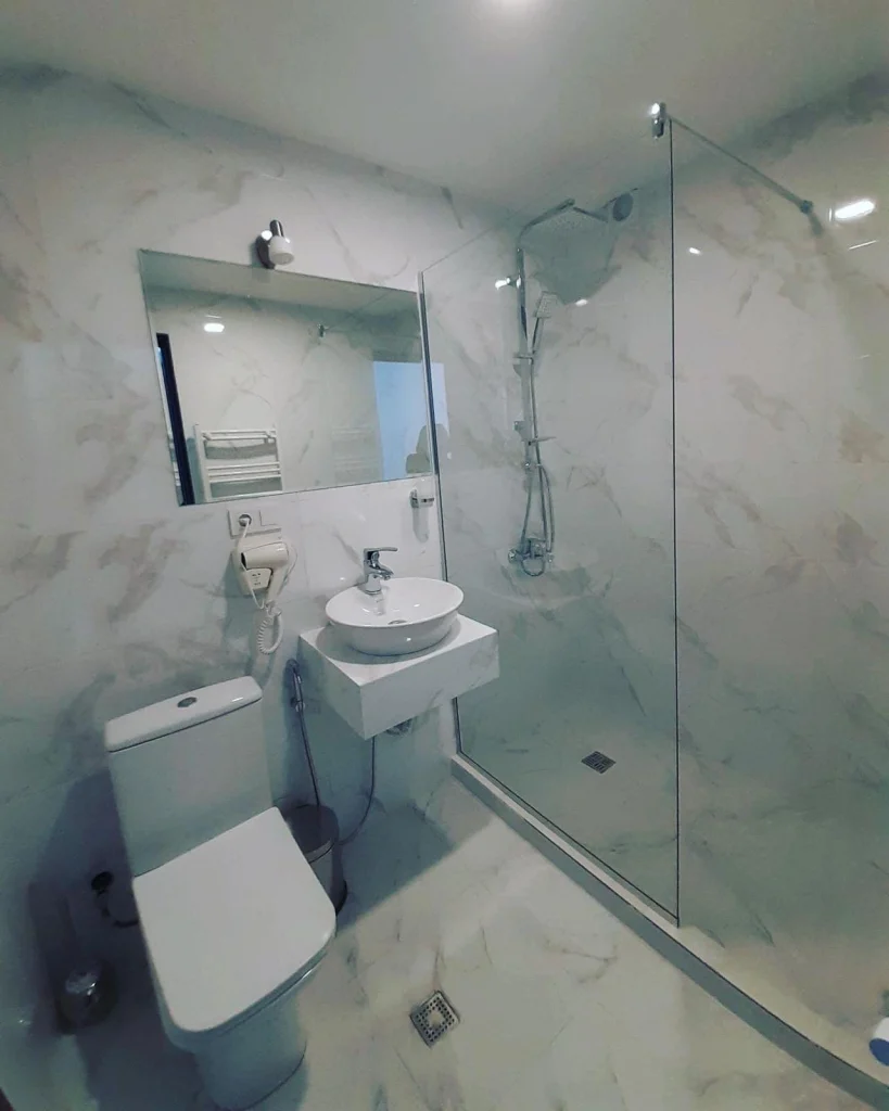 gudauri diamond — Modern marble bathroom with glass-enclosed shower, sink, and toilet.