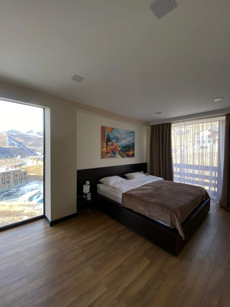 gudauri diamond — Bedroom with a large bed, wood flooring, and a floor-to-ceiling mountain-view window.