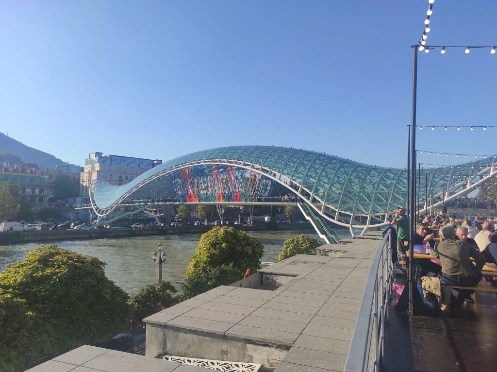 Crowds gather by the Bridge of Peace during a city festival, showing Tbilisi's everyday public life.