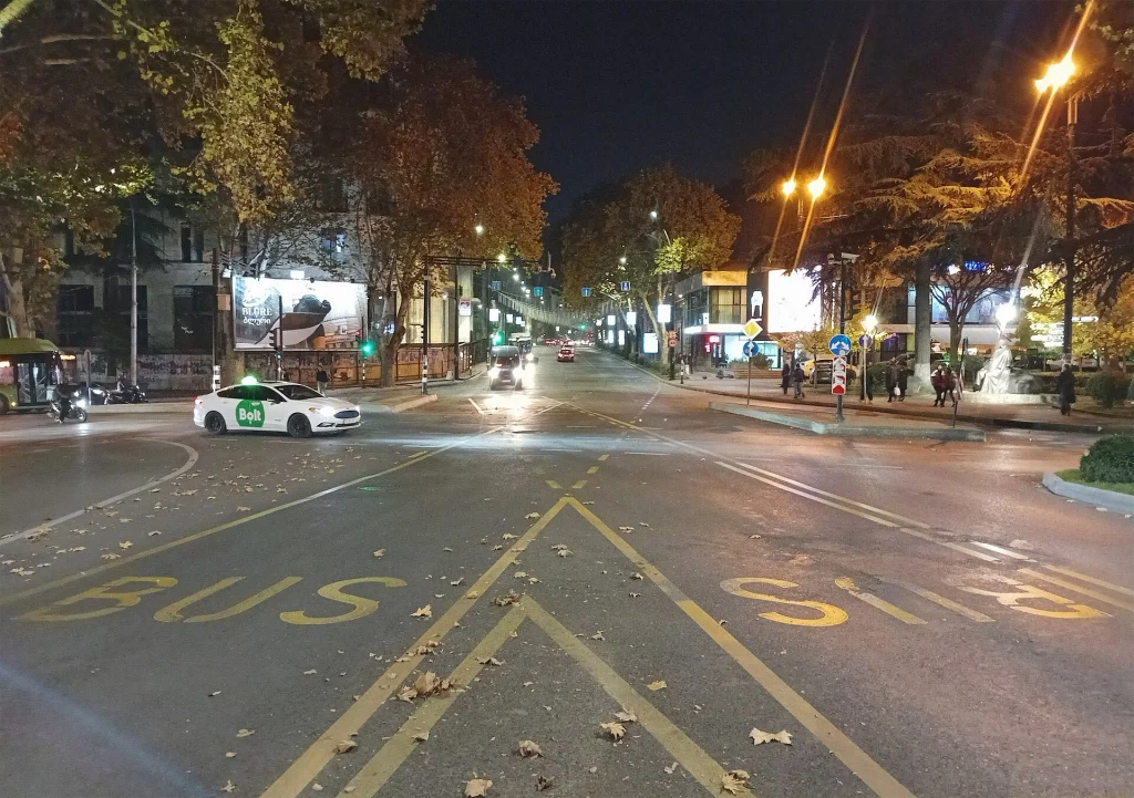 A taxi waits at a Tbilisi intersection at night, illustrating street taxi rides around the city.
