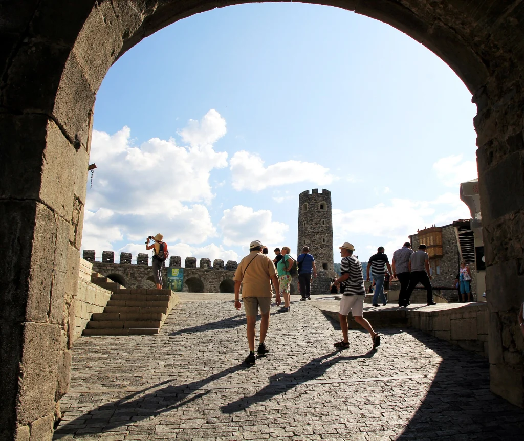 Tourists stroll through the stone archway entrance into Rabati Castle.