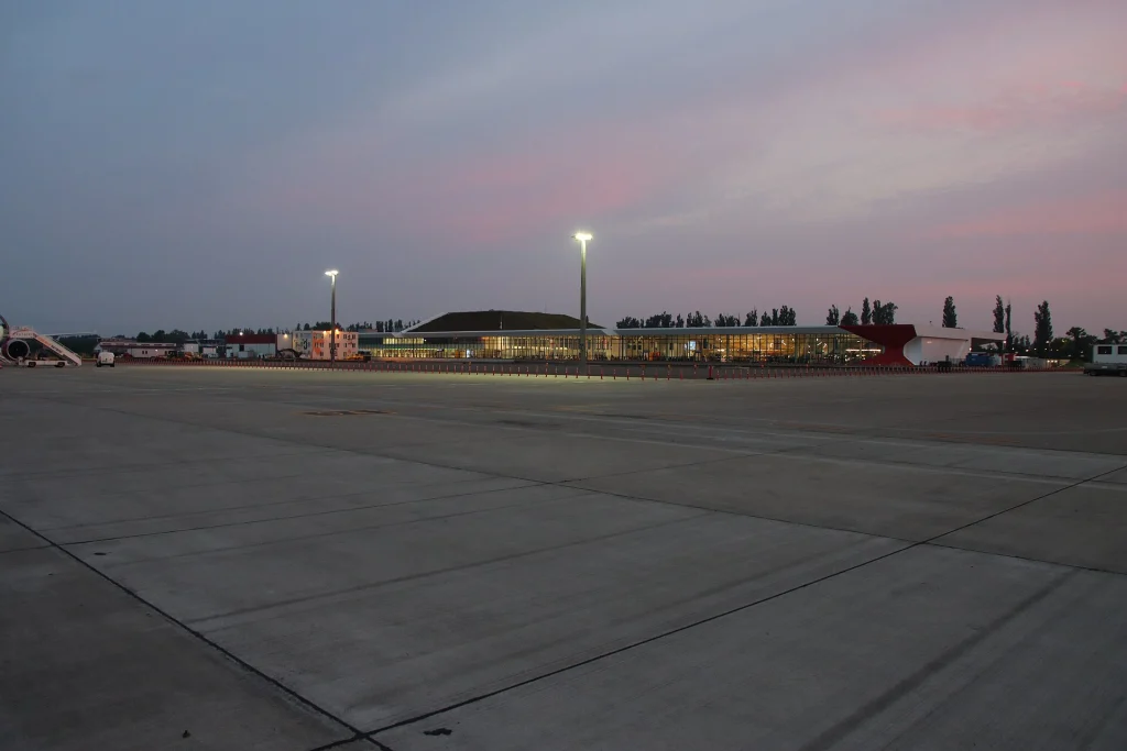 Kutaisi Airport terminal building at dusk with aircraft on the tarmac.