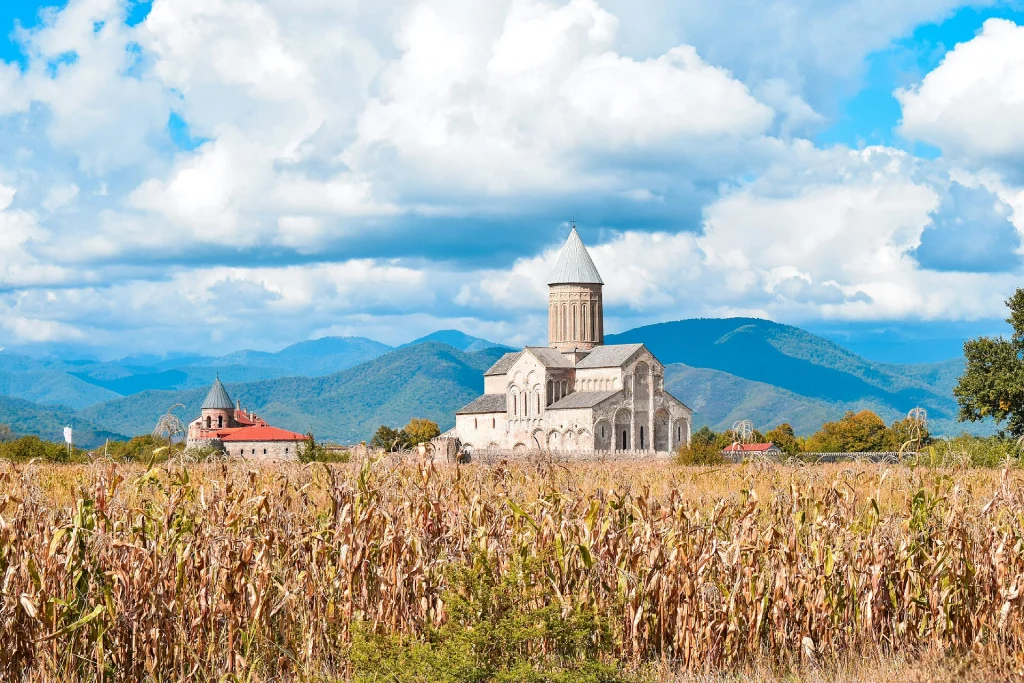 Alaverdi Cathedral viewed across a cornfield with the Caucasus mountains behind.