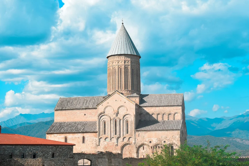 Alaverdi Cathedral's distinctive tower and dome stand against a dramatic sky with distant mountains.