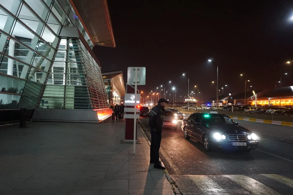 Taxi queue and police officer at the airport arrivals curb, Tbilisi.