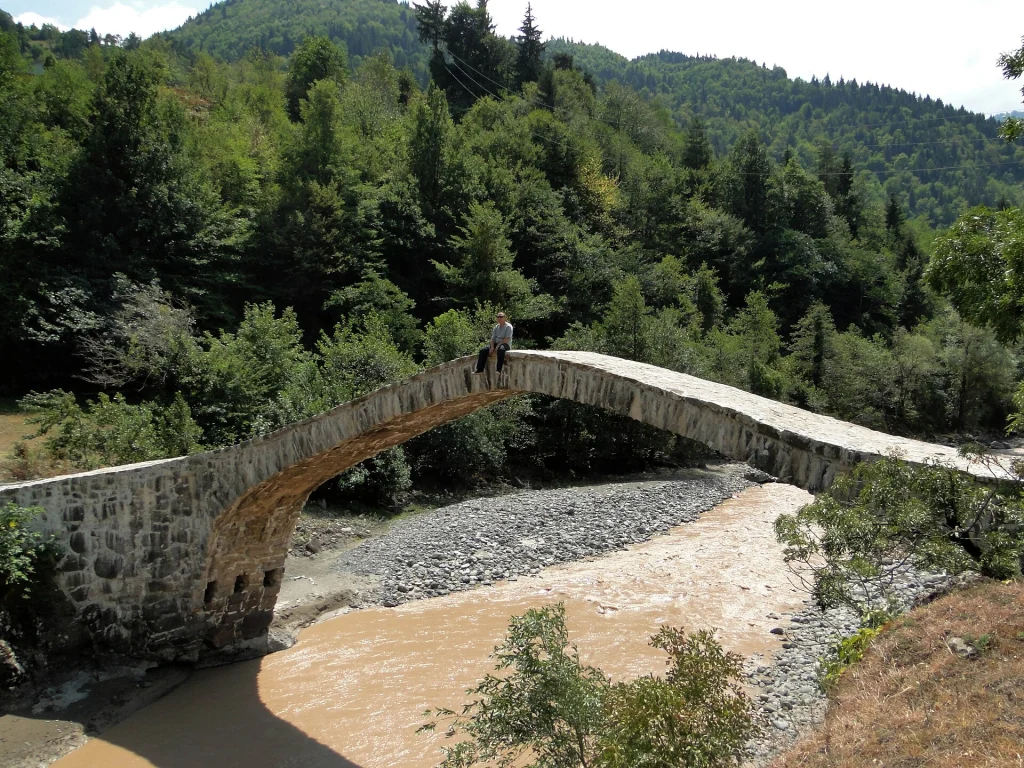 Arched stone bridge crossing a river surrounded by forested hills near Batumi, Georgia.