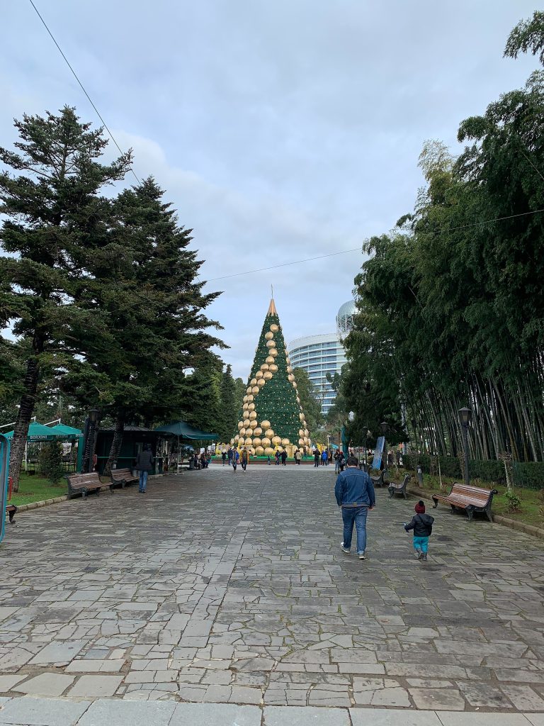 Families stroll along the decorated seafront promenade toward the lit New Year tree.