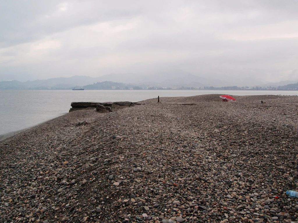 A quiet stretch of Batumi's characteristic pebbly beach with mountains in the distance.