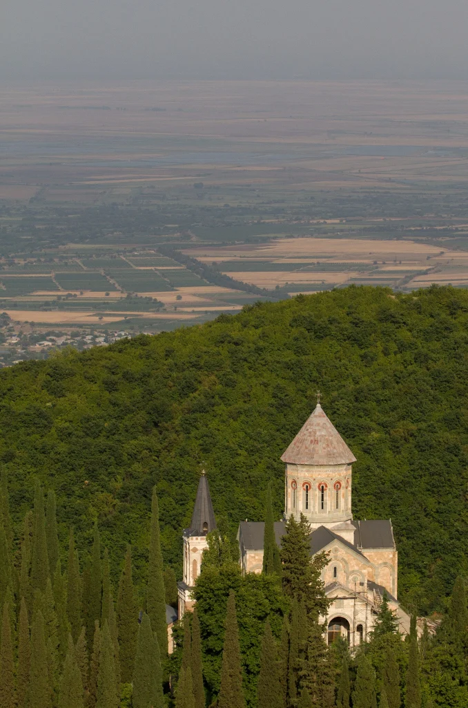 Bodbe Monastery nestled in green hillside overlooking the wide Alazani Valley below Sighnaghi.