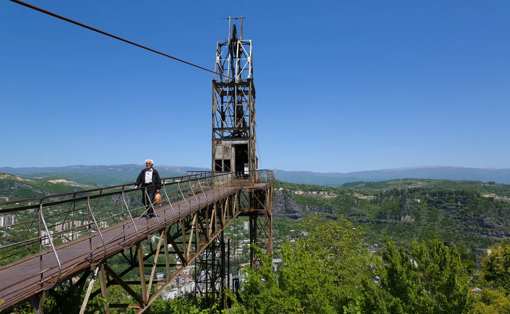 A visitor crosses one of Chiatura's dramatic aerial cable-car walkways overlooking the valley.