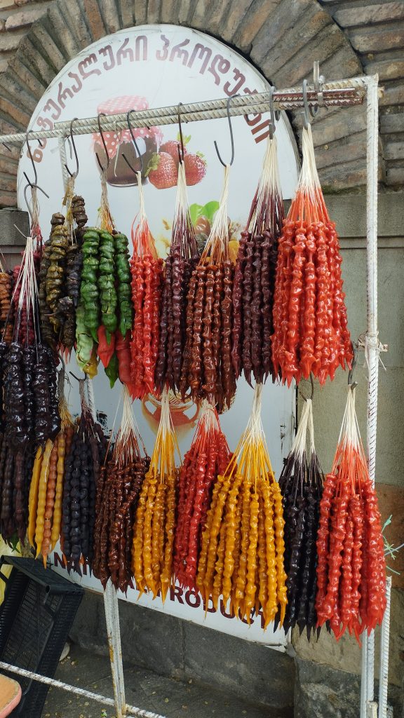 Colorful strings of churchkhela, a traditional Georgian sweet, hang at a festival stand.