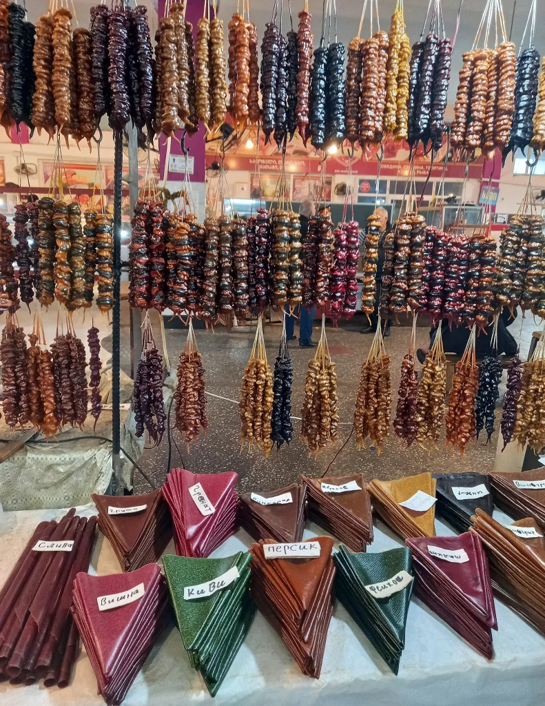 Rows of multicolored churchkhela hanging at a traditional Georgian food market.