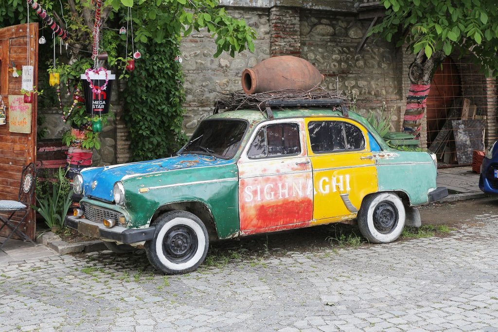 A whimsical hand-painted car labeled 'Sighnaghi' decorates a street corner in the town.