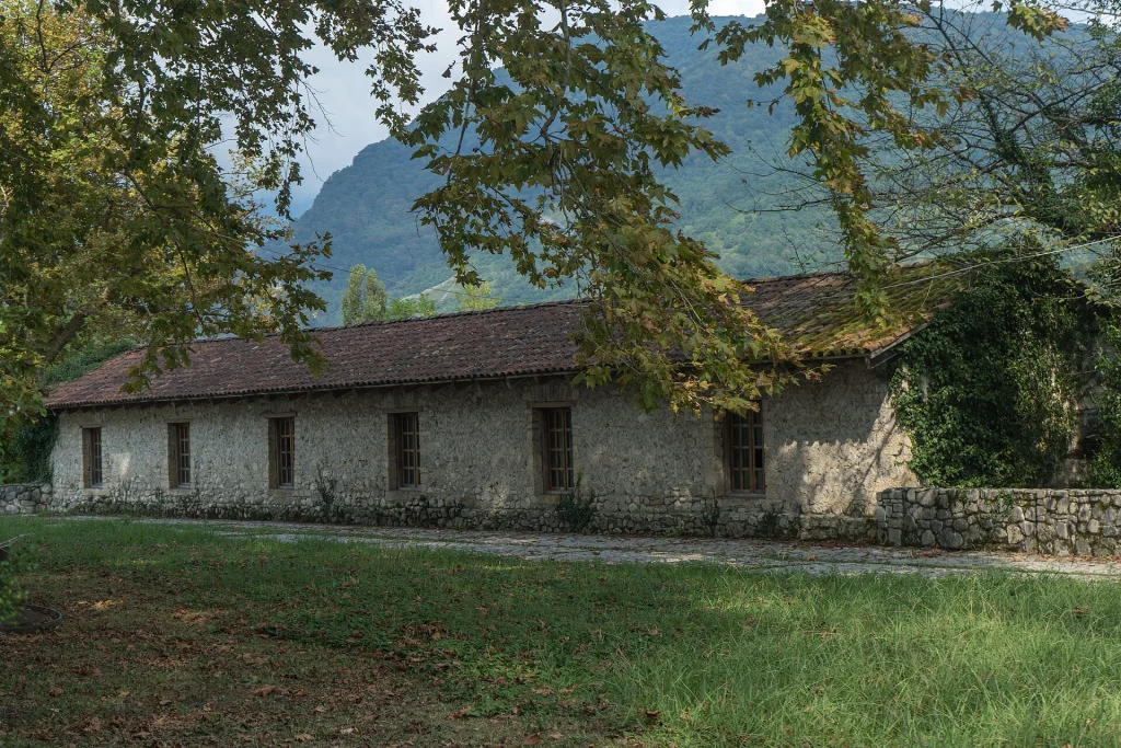 The historic Dadiani Wine Cellar building in Salkhino, nestled below forested mountains.