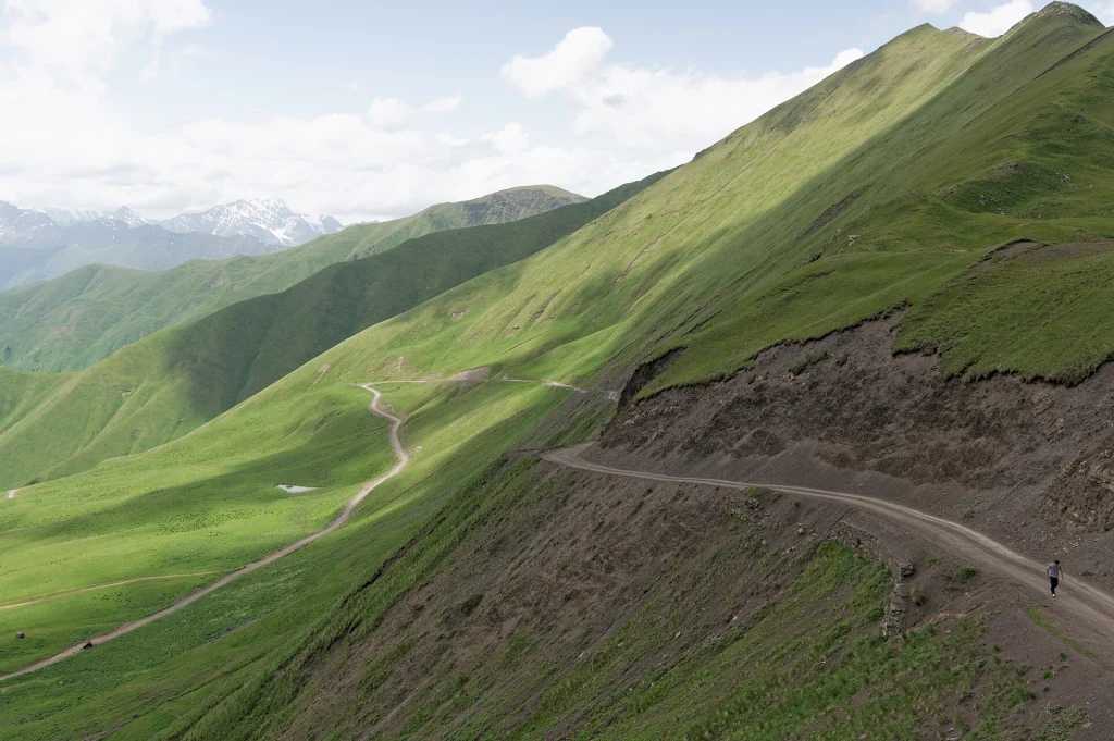 Winding dirt road climbing through green mountains at Datvisjvari Pass.