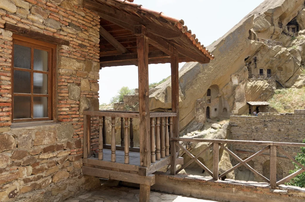 A traditional wooden balcony and rock-cut cells at David Gareja monastery complex.