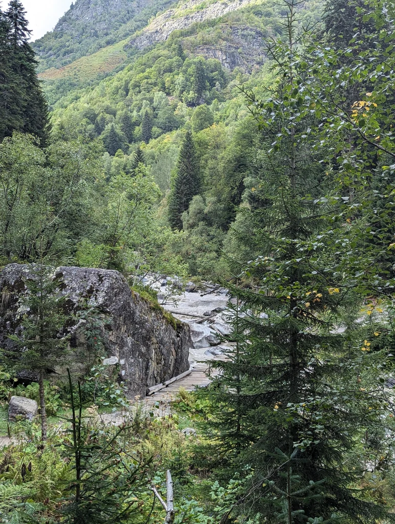 A wooden footbridge crosses the rocky Dolra River on the trail to Ushba.