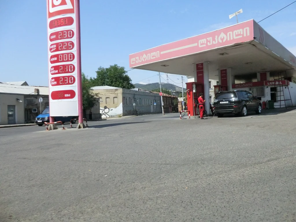 A car refuels at a Lukoil petrol station in Tbilisi, with prices displayed on the canopy pillar.