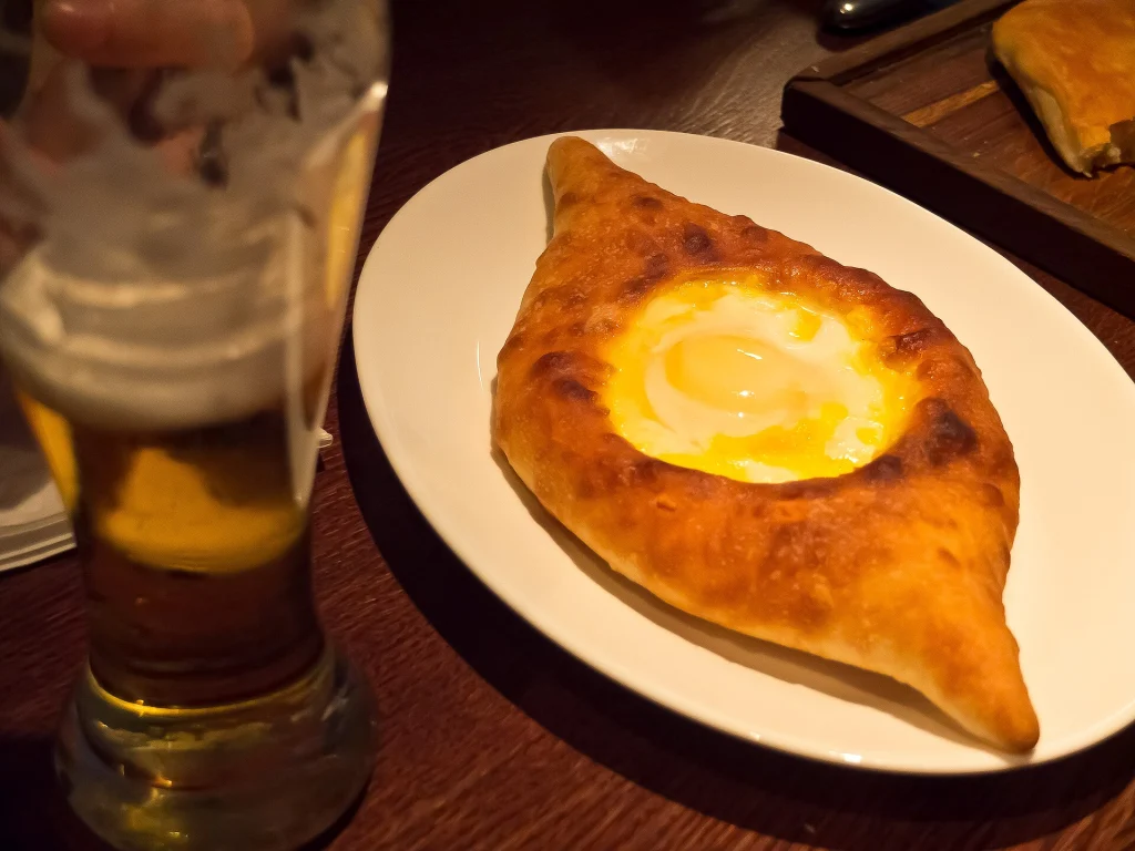 Adjarian-style khachapuri served with beer, a classic Georgian food experience for visitors.