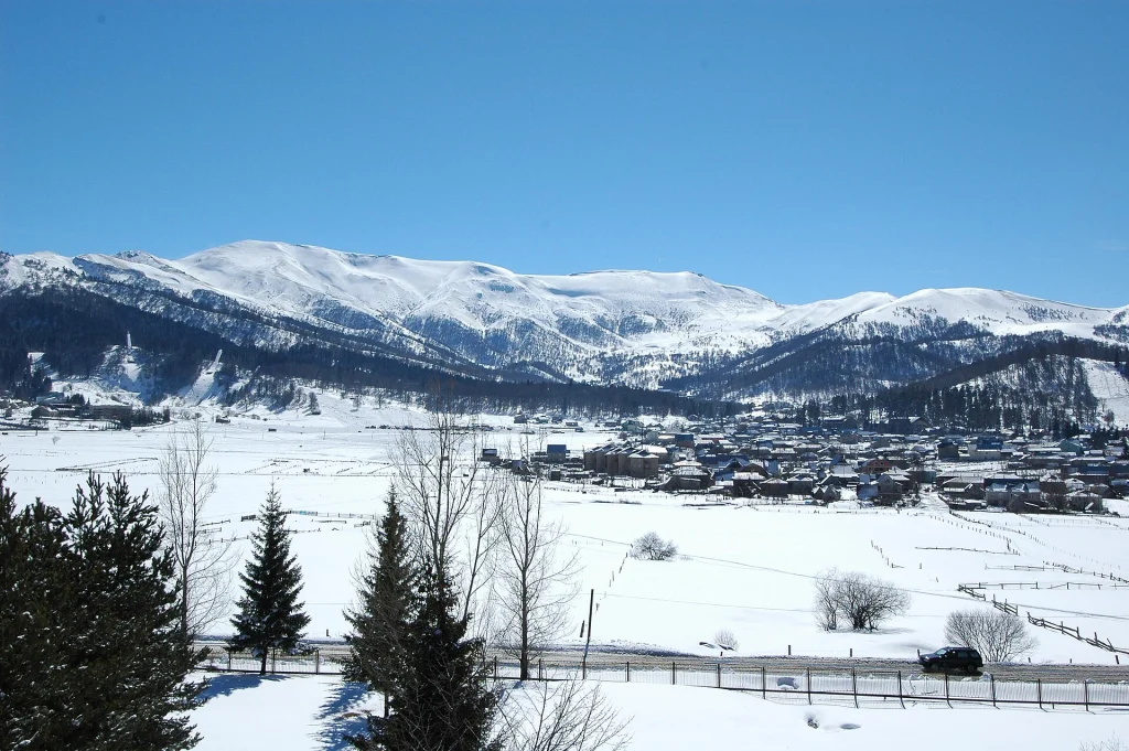 Panoramic winter view of Bakuriani town nestled beneath snow-capped mountains.