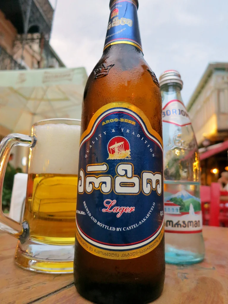 A Georgian lager and mineral water on a Tbilisi café table, a contrast to Czech beer traditions.