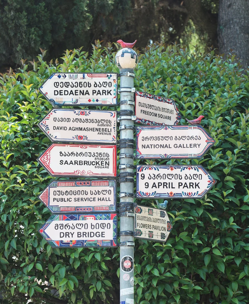 A Tbilisi fingerpost shows Georgian script paired with English transliteration for travellers.