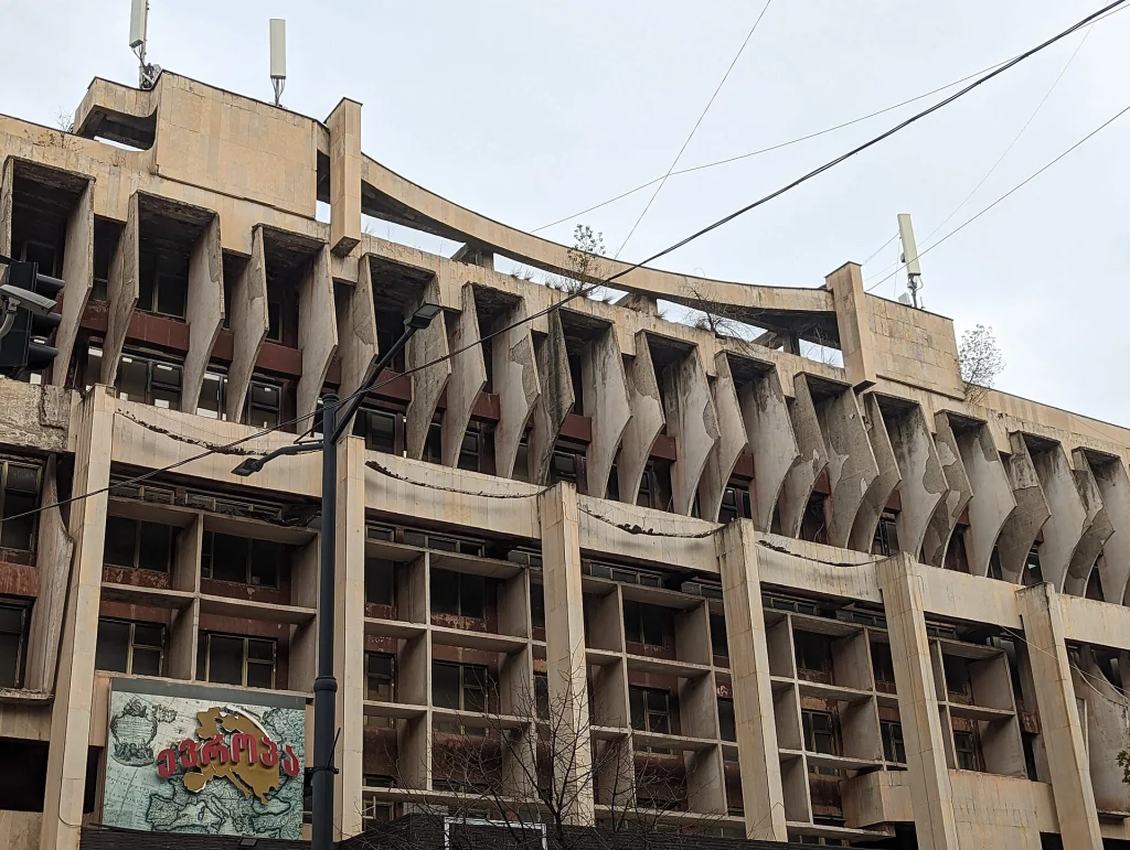 A weathered brutalist facade in Tbilisi shows the concrete style the hotel's renovation reinterprets.