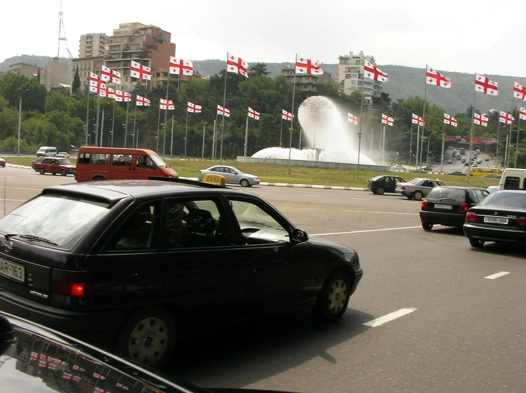 A taxi among traffic in Tbilisi, representing taxi drivers who may expect a tip.