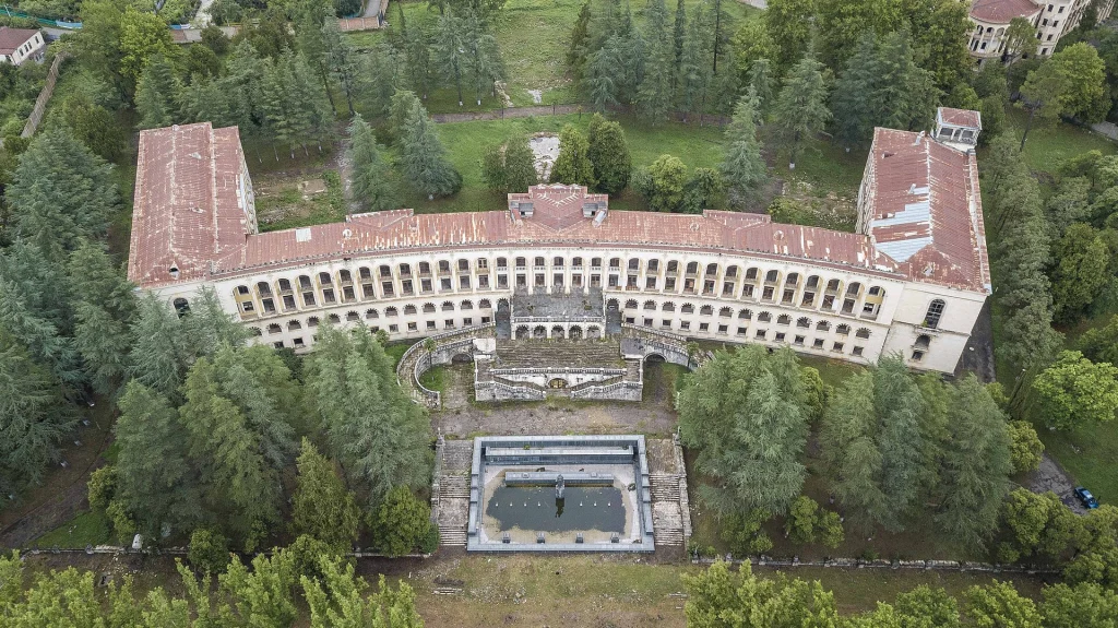 Aerial view of the grand U-shaped Meshakhte Sanatorium bathhouse surrounded by forest in Tskaltubo.