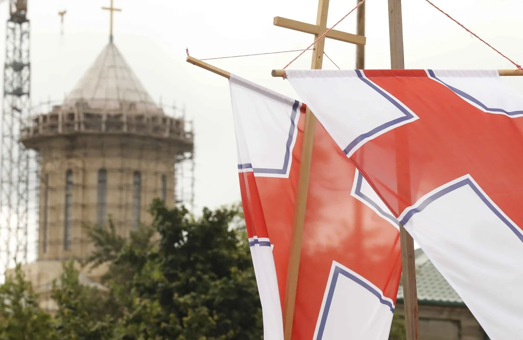 Georgian Orthodox Church flags fly before a cathedral during a religious procession in Georgia.