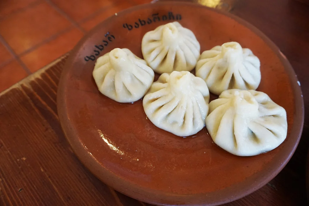 Traditional Georgian khinkali dumplings served on a clay plate.