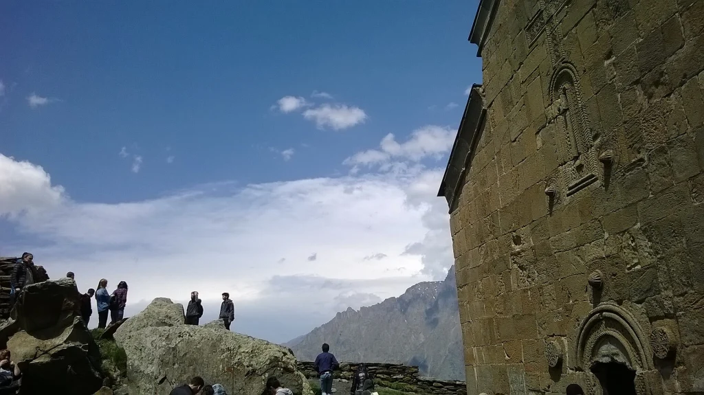 Tourists at Gergeti Trinity Church, one of Georgia's most iconic landmarks near the mountains.