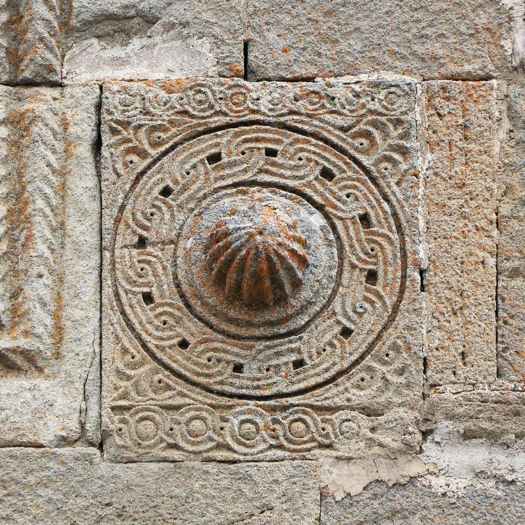 Detailed medieval stone carving on the exterior wall of Gergeti Trinity Church.