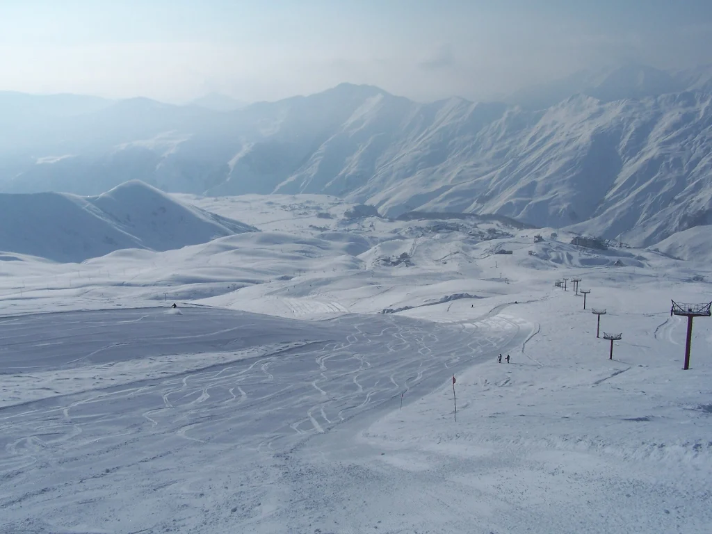 Snow-covered valley and ski slopes with mountain range at Gudauri resort.