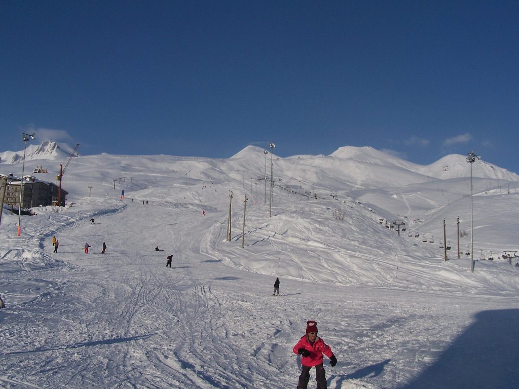 A snowboarder descends the Gudauri piste beneath the surrounding Caucasus peaks.