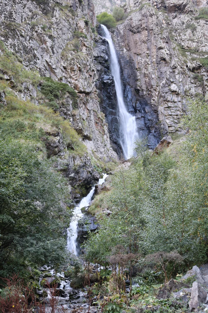 Gveleti waterfall plunges through cliffs surrounded by lush green vegetation.