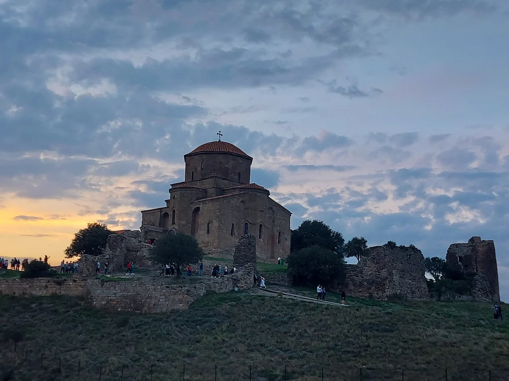 Pilgrims and tourists gather at dusk outside Jvari Monastery near Mtskheta.