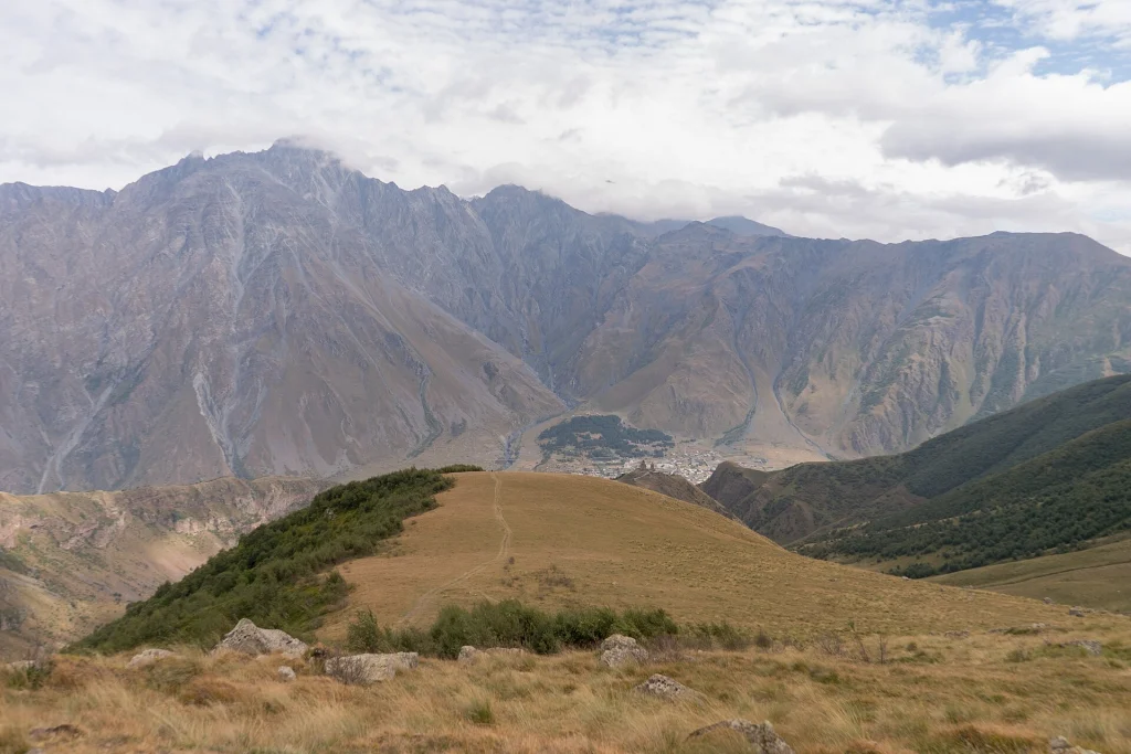 The winding trail to Gergeti Glacier traces a ridge above the Stepantsminda valley.
