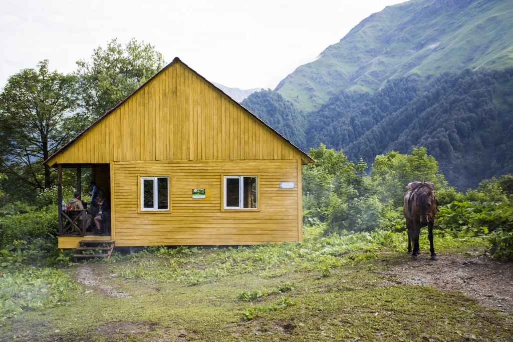 Wooden ranger shelter with a pack horse grazing beside the trail in Lagodekhi's mountains.