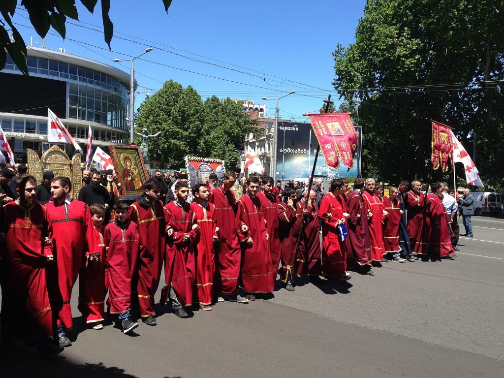 Priests in scarlet robes carry icons and banners during the family sanctity holiday march.