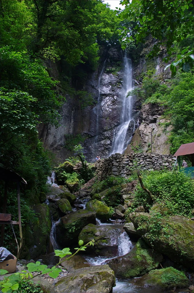Makhuntseti waterfall cascading down a rocky cliff surrounded by lush green forest in Adjara.