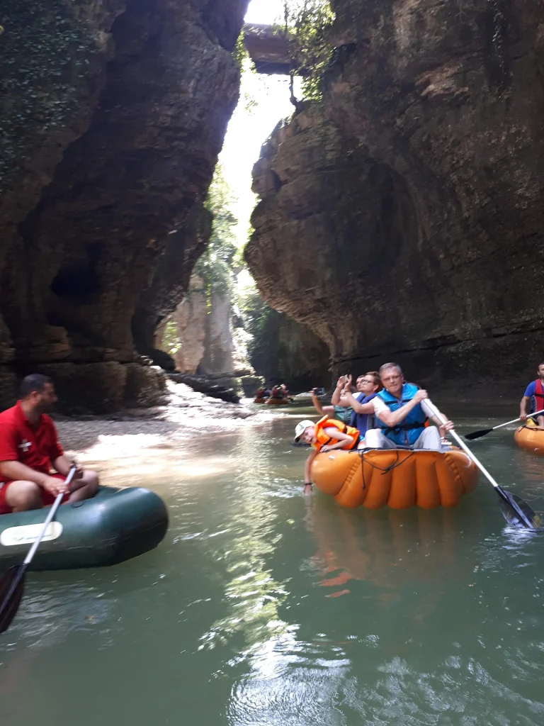 Visitors paddle inflatable boats through the dramatic rock walls of Martvili Canyon.
