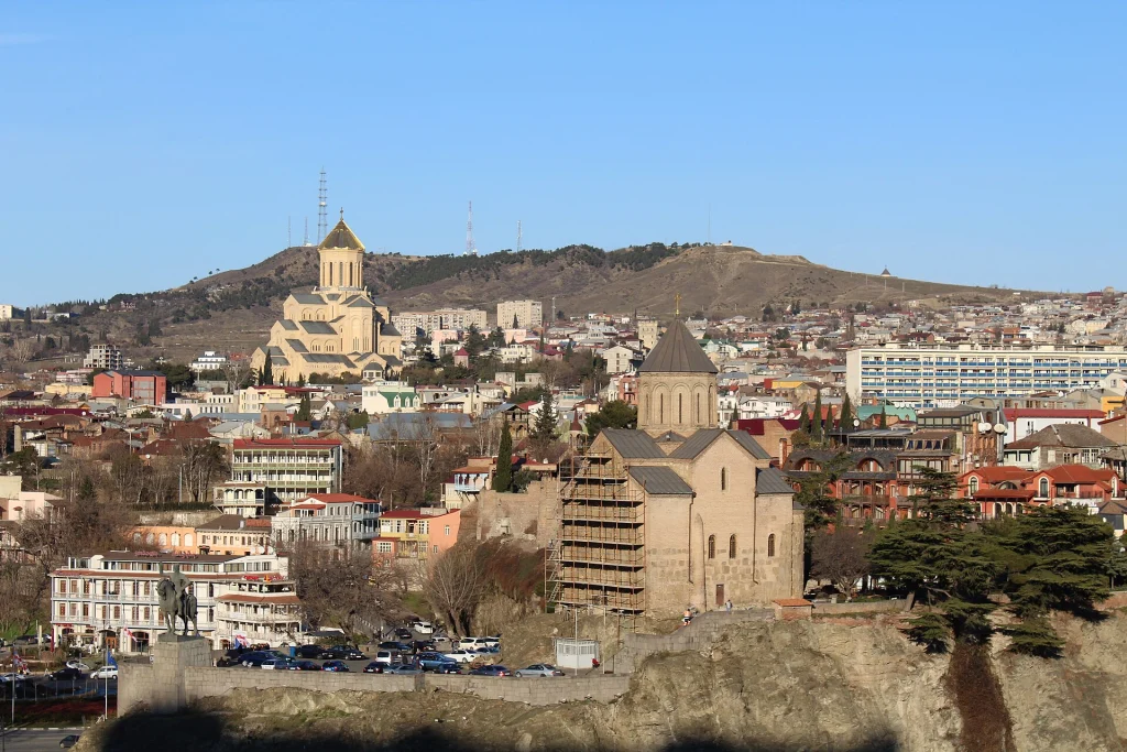 A panoramic view of Tbilisi's old town skyline with the historic Metekhi Church on the cliff.