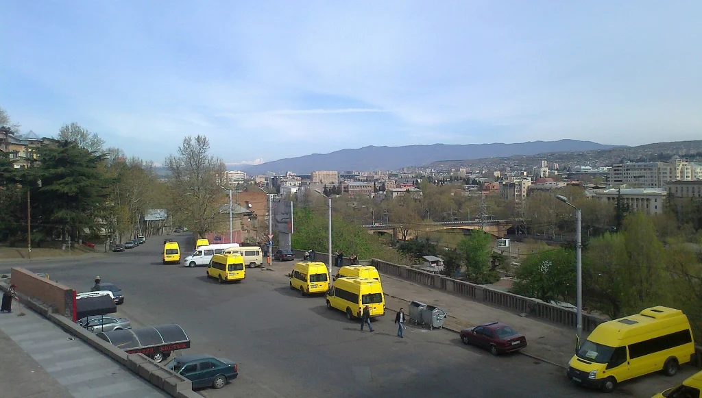 Minibuses line up in downtown Tbilisi with the Caucasus mountains in the background.