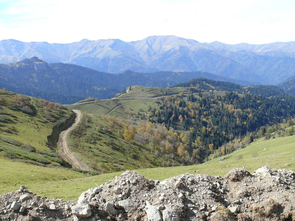 A winding mountain dirt road leading toward the forested peaks near Sairme's highland springs.