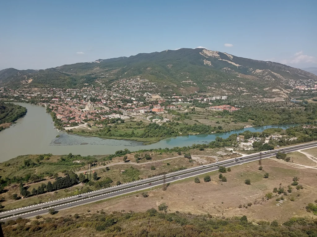 Aerial view of the Mtkvari and Aragvi rivers meeting near Mtskheta beneath forested mountains.