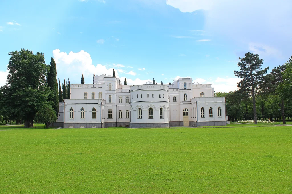 Château Mukhrani palace seen from across a manicured green lawn.